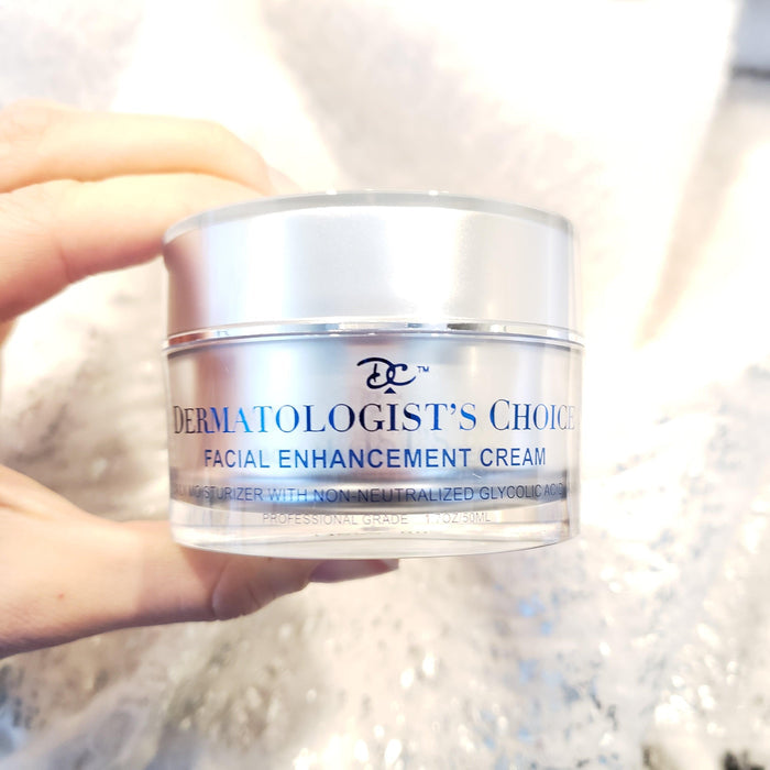 Hand holding a jar of Facial Enhancement Cream Mild Glycolic Daily Moisturizer | Dermatologist's Choice, skincare product in a translucent container with silver lid.
